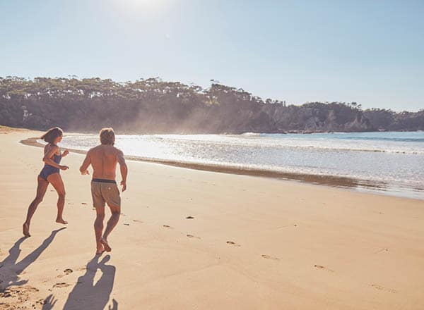 Couple running along McKenzies beach